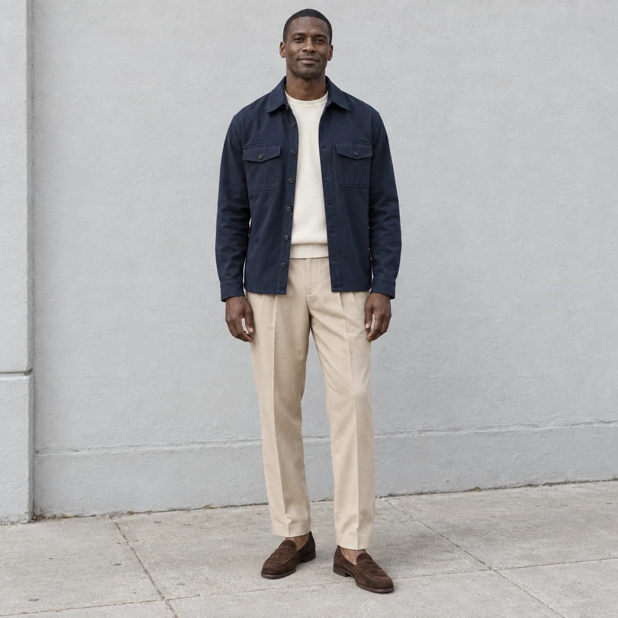 Outfit reference: a man in a navy overshirt, cream sweater, beige trousers and brown loafers.